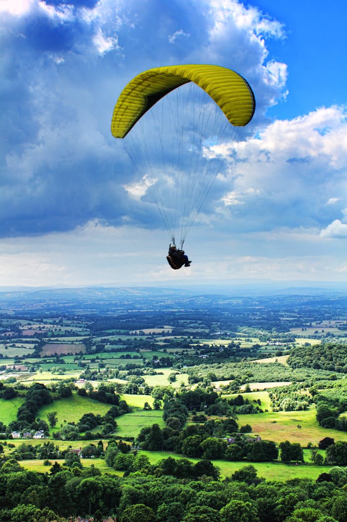 Experience thrilling paragliding over scenic Malvern Hills under a vibrant summer sky.